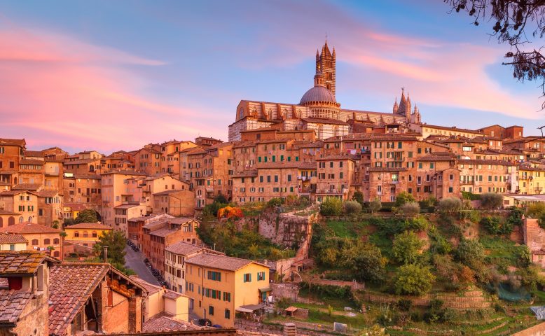 Beautiful view of Dome and campanile of Siena Cathedral, Duomo di Siena, and Old Town of medieval city of Siena at gorgeous sunset, Tuscany, Italy